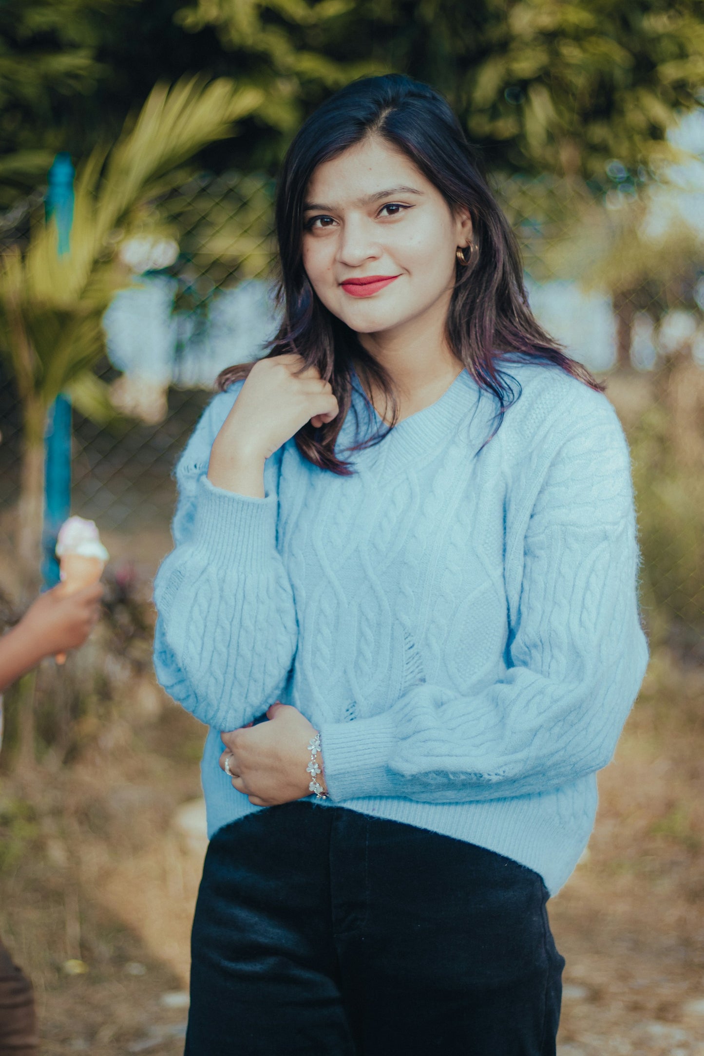 Woman in a light blue sweater holding an ice cream cone outdoors